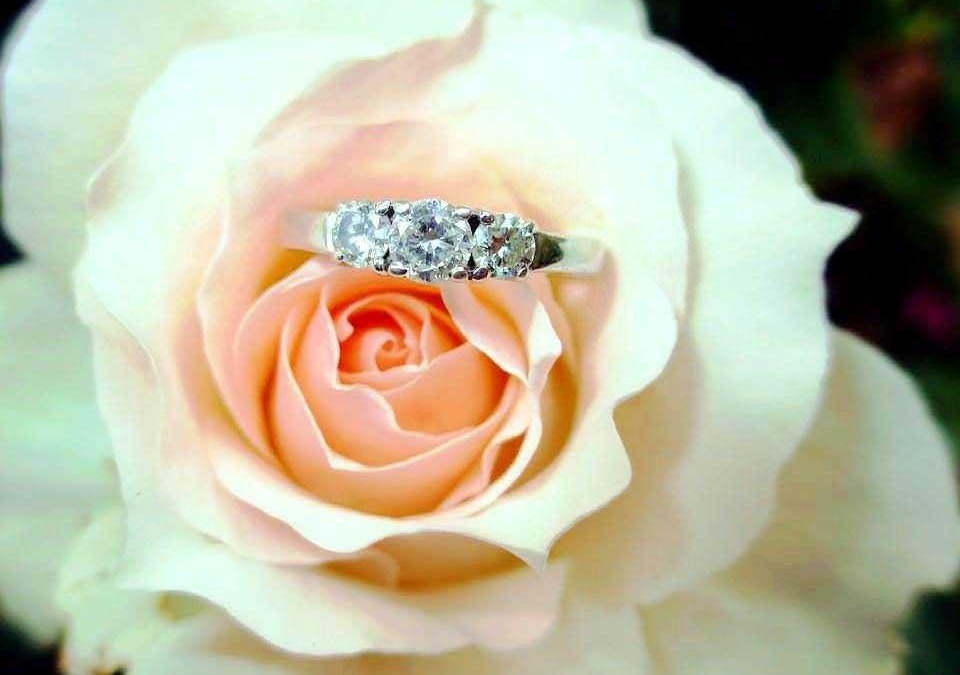 Elegante anello di diamanti posto su una rosa bianca, simbolo di amore e bellezza. Perfetto come regalo di fidanzamento o matrimonio, esalta il fascino dei gioielli in oro e diamanti.