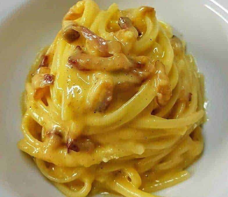 Crema di pancetta e formaggio su spaghetti carbonara, piatto italiano classico, cucina autentica, ricetta tradizionale.
