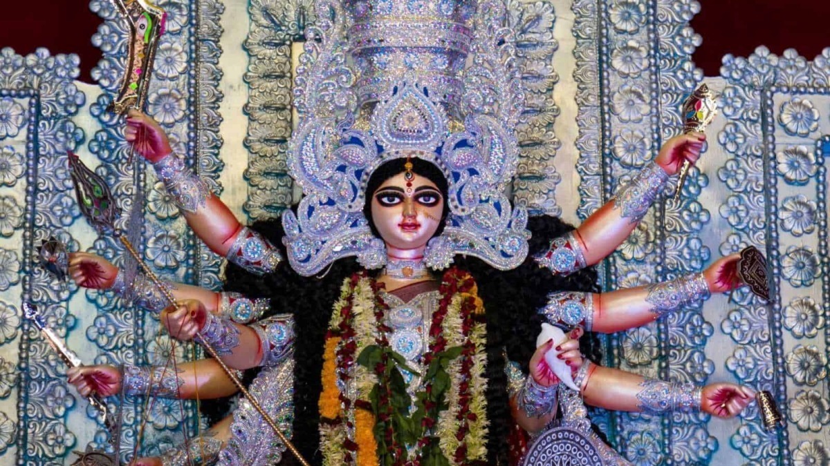Multicolore statua di hinduismo di Devi Durga con nove braccia, decorata con gioielli e fiori, in un contesto spirituale.