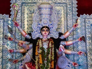 Multicolore statua di hinduismo di Devi Durga con nove braccia, decorata con gioielli e fiori, in un contesto spirituale.