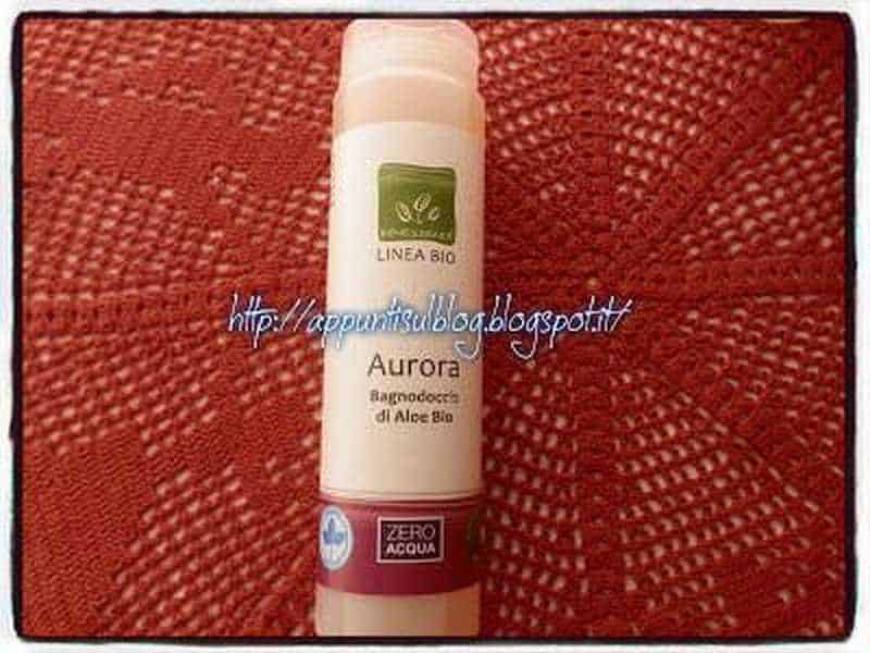 Pianta Aurora di Aloe Bio in flacone, pronto all'uso, senza acqua, ideale per prodotti naturali e biotecnologie verdi, su sfondo tessile rosso.