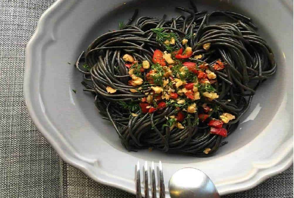 Spaghetti nero di seppia con olio, aglio, prezzemolo e peperoncino, piatto di pasta elegante e saporito, cucina italiana autentica, ingredienti freschi, presentazione invitante.