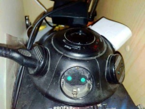 Plugged-in vacuum cleaner with power cord and control buttons on a modern device for home cleaning.