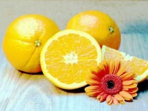 Gialli pompelmi freschi con fiori arancioni su superficie di legno naturale.