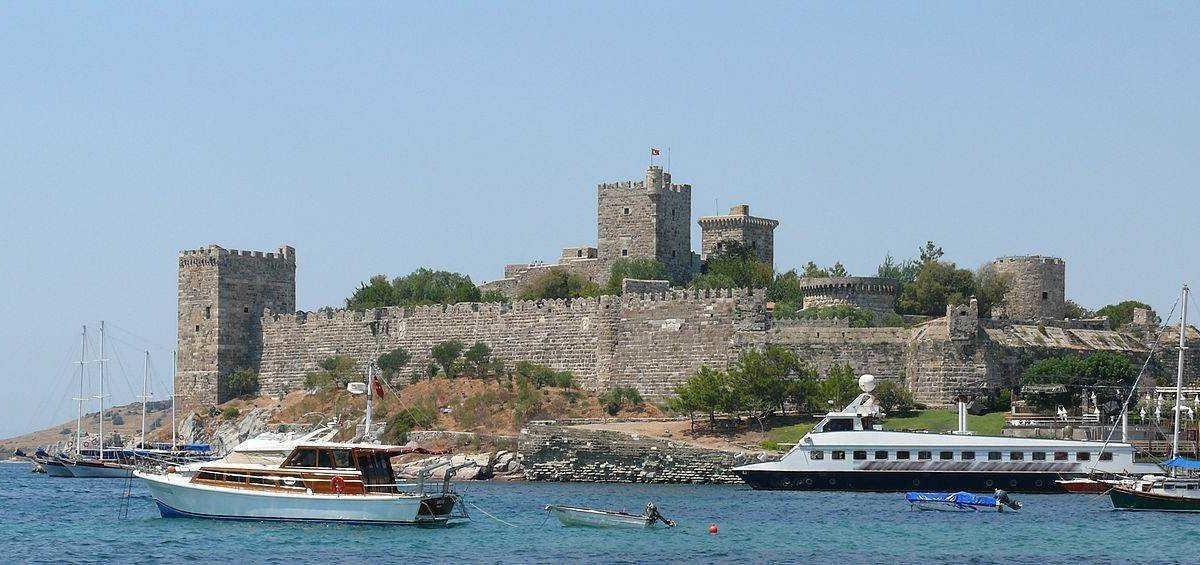 Castello storico con imbarcazioni in mare, vista panoramica di fortezza medievale su costa, turismo nautico e paesaggi costieri, località turistica in Italia, Appunti Sul Blog.