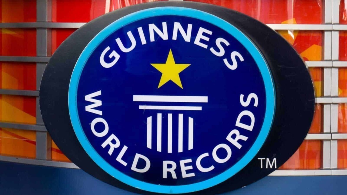 Guinness World Records logo su sfondo colorato con schede di gioco e strisce tendina blu.