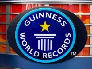 Guinness World Records logo su sfondo colorato con schede di gioco e strisce tendina blu.