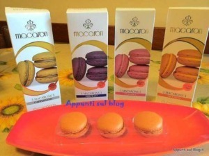 Cuorenero: Macarons assortiti in varie varianti di colore, presentati con confezioni eleganti su fondo floreale.