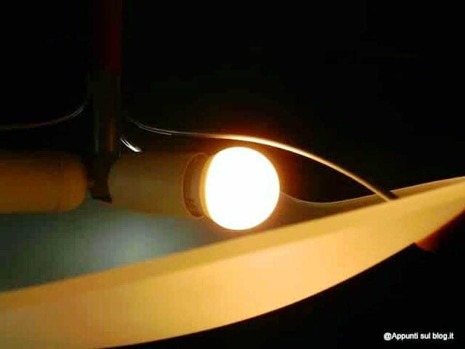 Lampada da tavolo accesa con luce calda su scrivania, ambiente di lavoro o studio, illuminazione morbida ed accogliente per lettura o scrittura, ideale per shop online o blog di lifestyle.