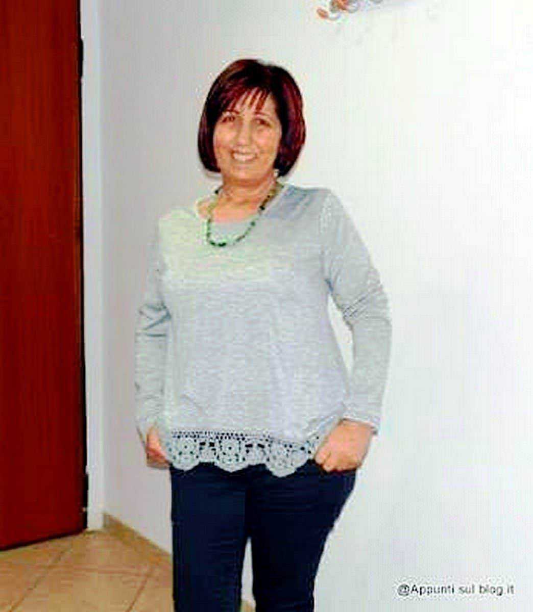 T-shirt a fiori long sleeve crochet: Elegante donna con capelli corti e rosso castano, indossa maglia grigia stile casual e pantaloni scuri, in ambientazione domestica, sorridente e sicura di sé.