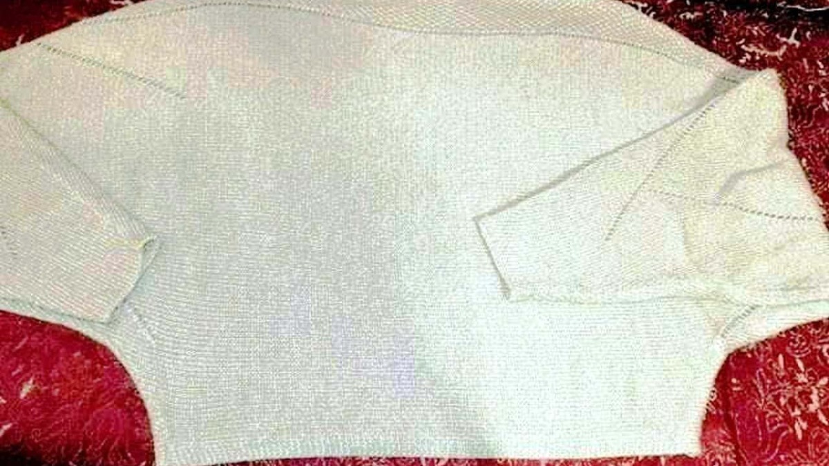 Tessuto di maglia bianca per produzione di abbigliamento, disposto su sfondo rosso con motivi floreali. Ottimo esempio di tessuto per la moda e il design di moda contemporaneo.