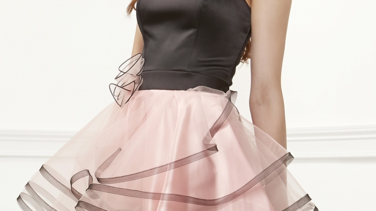 Vestito femminile elegante con gonna rosa svasata e top nero, scarpe a tacco alto e sorriso luminoso, stile fashion e femminile, perfetto per occasioni speciali.
