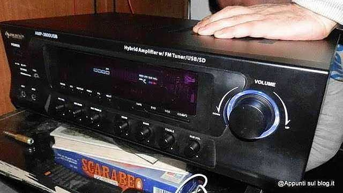 Amplificatore stereo con tuner FM e lettore USB SD, controlli di volume e equalizzatore, posizionato su una scrivania con libri e accessori audio, ideale per impianti hi-fi domestici.