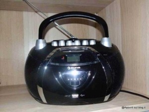 Radio portatile nero con manico, tasti e display digitale, ideale per ascoltare musica e radio in movimento.
