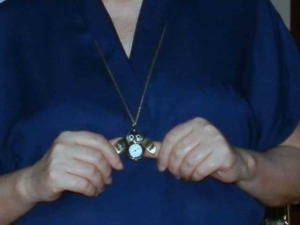 Orologio da tasca vintage con catenina, accessorio di stile elegante e retrò, indossato da donna con abbigliamento blu scuro. Accessori moda, vintage, orologi da tasca.