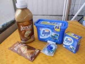 Profumo Lenor, Detergente Dash 3 in 1 e sapone in polvere per bucato su superfice arancione. Prodotti per il lavaggio e l'igiene della casa, ideali per mantenere tessuti puliti e profumati.