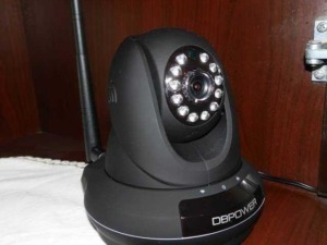 Telecamera di sorveglianza con LED IR, dotata di antenna wireless per la trasmissione dei dati, posizionata su superficie in legno. Perfetta per sicurezza e sorveglianza domestica o aziendale.