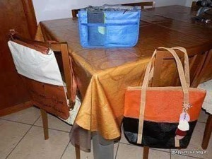 Cestino per rifiuti blu e borsa beige con dettagli arancioni sul tavolo di legno in cucina.