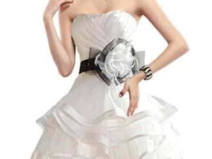 Elegante donna in abito bianco con cintura nera e accessori moda, posa su sfondo bianco, stile sofisticato e chic.