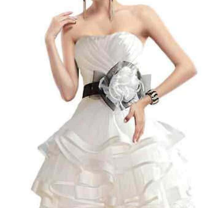 Elegante donna in abito bianco con cintura nera e accessori moda, posa su sfondo bianco, stile sofisticato e chic.