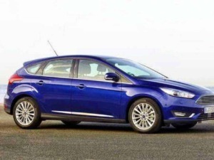 Ford Focus hatchback blu su strada con sfondo mare all'aperto, auto moderna e elegante perfetta per viaggi e città, design aerodinamico e dettagli sofisticati.