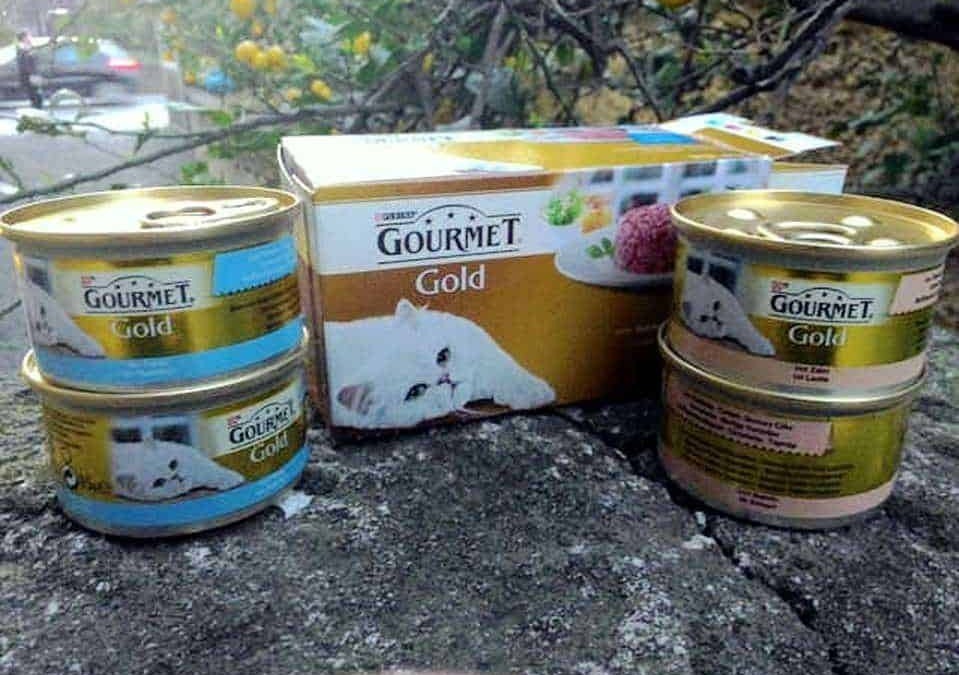 Gourmet Gold cibo per gatti scatole e lattine di cibo umido per felini, immagine con confezioni di alimenti feline di alta qualità.