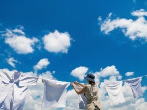 Lavatrici stese al sole sotto un cielo azzurro con nuvole bianche, simbolo di pulizia e freschezza, rappresentano la cura della casa e il buon clima.