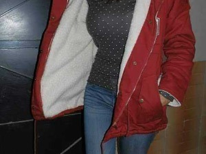 Scarpa invernale donna con interno peloso, giacca rossa con cappuccio e punte in pelliccia, jeans blu, outfit casual elegante in inverno.