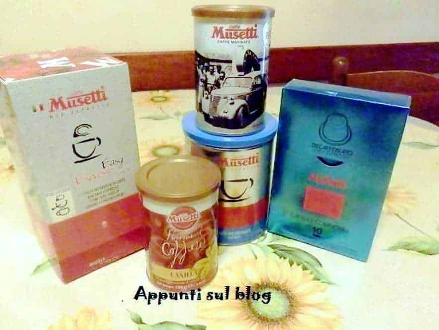 Musetti caffè in varie confezioni, con una scatola e barattoli sul tavolo, ambiente casalingo, prodotti di alta qualità per il caffè, promozione di aromi e sapori italiani.