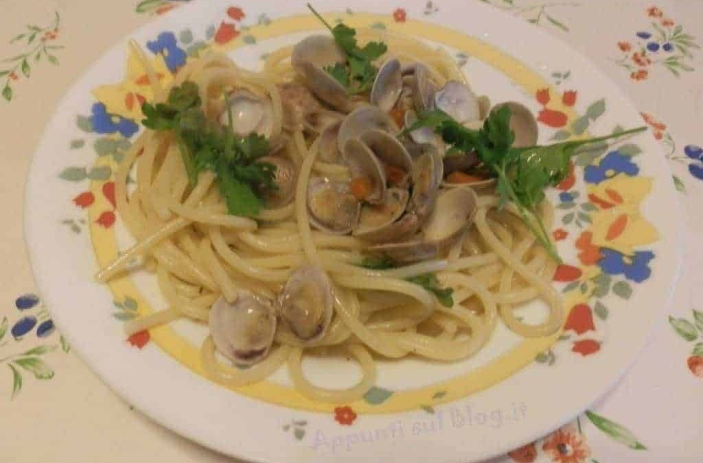 Vongole e spaghetti freschi preparati con ingredienti di alta qualità, serviti in un piatto decorato con erbe aromatiche, ideale per un pranzo di mare autentico e saporito.