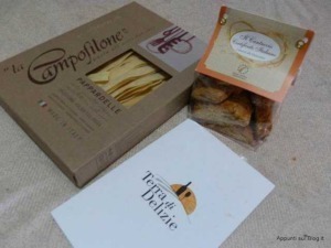 Fascetta di pasta pappardelle La Timpolone, biscotti artigianali e cartolina con scritta Terra di Delizie, immagini di prodotti tipici italiani e confezioni alimentari di alta qualità.