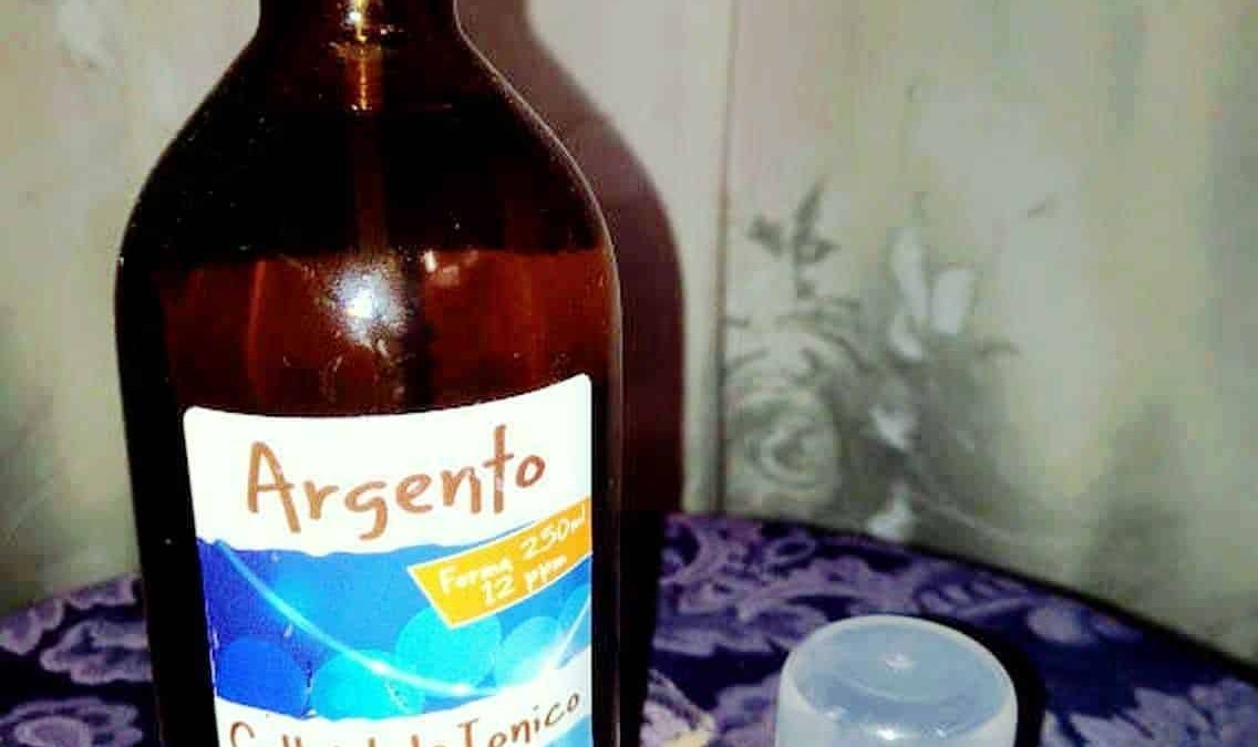 Argento colloidale in bottiglia di vetro marrone con spray, usato come trattamento naturale per il benessere e l'igiene personale.