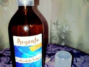 Argento colloidale in bottiglia di vetro marrone con spray, usato come trattamento naturale per il benessere e l'igiene personale.