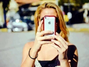 Iphone usato per scattare foto in viaggio con sfondo urbano, donna con capelli rossi, digitale, tecnologia moderna, social media, appunti sul blog.