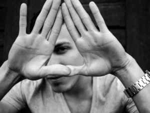 - Hands form a triangle around one eye, black and white photo.