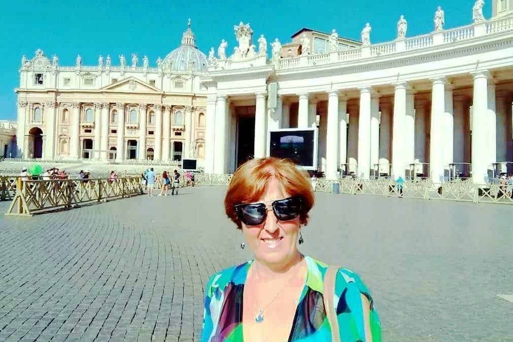 Majestosa Basilica di San Pietro a Roma con visitatrice sorridente in primo piano, abbigliamento colorato, giornate soleggiate, turisti, architettura storica, pellegrini.