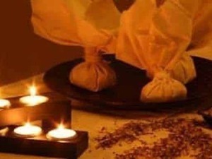 Ciotole di tessuto riempite di erbe aromatiche per aromaterapia e benessere, posizionate su una superficie con candele accese che creano un'atmosfera rilassante e intima.