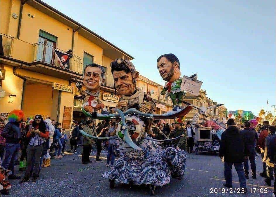 Carro allegorico con testine giganti durante una parata mascherata in strada in occasione di un carnevale, pubblico che osserva e partecipa alla festa, atmosfera vivace e colorata.