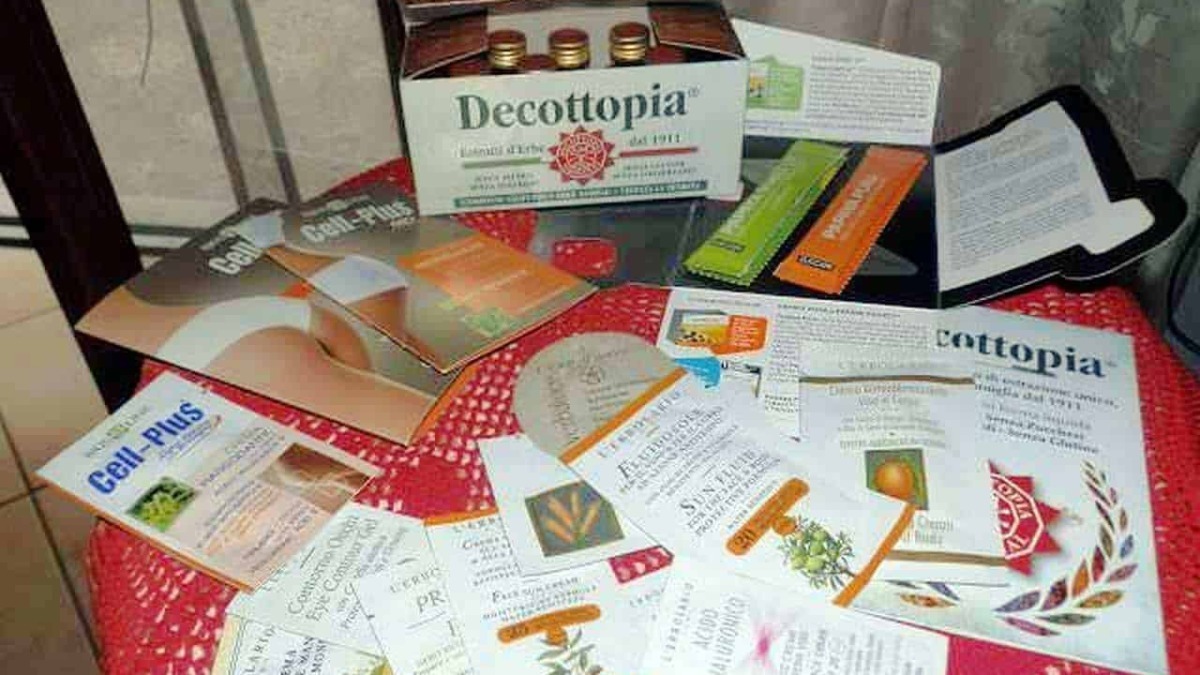 Foglie di decottopia, brochure e campioni di prodotti naturali su tavolo rotondo decorato con tovaglia rossa.