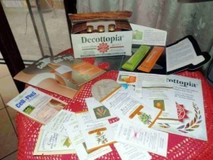 Foglie di decottopia, brochure e campioni di prodotti naturali su tavolo rotondo decorato con tovaglia rossa.