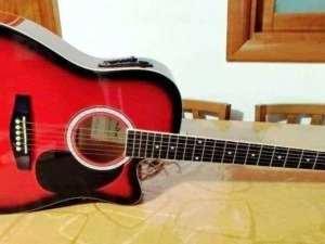 Guitar acustica rossa su tavolo, strumenti musicali, musica, suoni e creatività, ideale per blogger e appassionati di musica, perfetta per contenuti musicali e blog di musica.