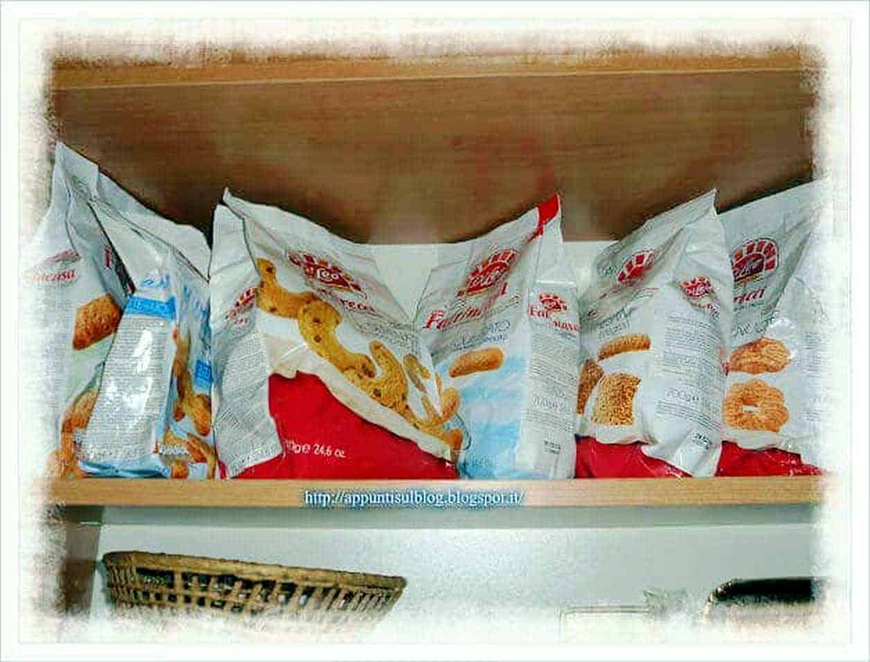 Pacchi di snack sul ripiano di una cucina, posizionati ordinatamente e pronti per essere consumati, con logo visibile.