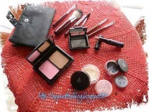 Pennelli per trucco, palette di cipria e prodotti cosmetici su tavolo rotondo con tovaglia rossa, focus su make-up e beauty essentials.