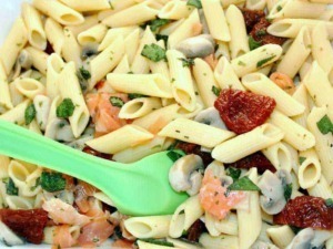 Pasta di penne integrali con funghi, pomodori secchi e erbe fresche in un piatto di cucina italiana fresca e salutare.