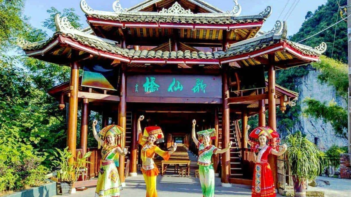Architettura tradizionale asiatica con corso di danza folkloristica all'aperto vicino a montagne verdi e vegetazione rigogliosa.