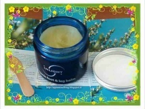 Crema per il trattamento di varici, gambe gonfie e problemi circolatori, contenuta in un vasetto blu con etichetta INLIGHT, immersa in un ambiente naturale e colorato con decorazioni floreali.