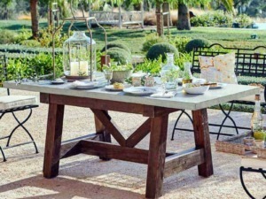 Rustic outdoor dining table con decor estivo per pranzo all'aperto in giardino, atmosfera rilassante e naturale, perfetta per cene estive e momenti conviviali all'aria aperta.