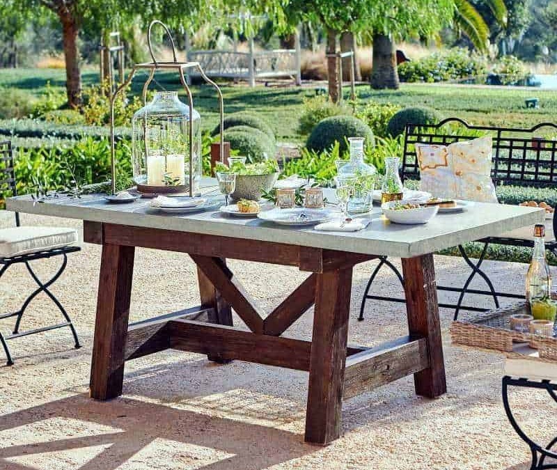 Rustic outdoor dining table con decor estivo per pranzo all'aperto in giardino, atmosfera rilassante e naturale, perfetta per cene estive e momenti conviviali all'aria aperta.
