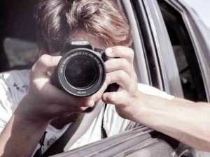 FOTO DI UN RAGAZZO CHE FA UNA SELFIE CON LA MACCHINA FOTOGRAFICA DAL FINESTRA DEL VEICOLO.