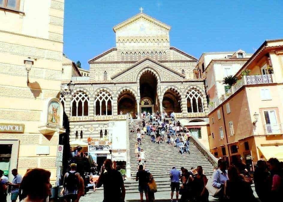 Immagine della chiesa di Santa Chiara e dei suoi iconici gradini a Napoli, con visitatori che salgono e scendono, catturando l’atmosfera vivace di un centro storico italiano.
